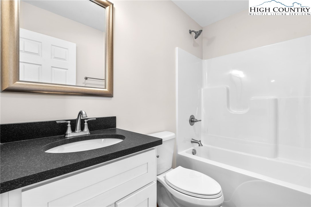 245 Ava Way, Unit 108 Boone, NC 28607 - Photo 21 of 29 a bathroom with a granite countertop sink toilet a mirror and bathtub