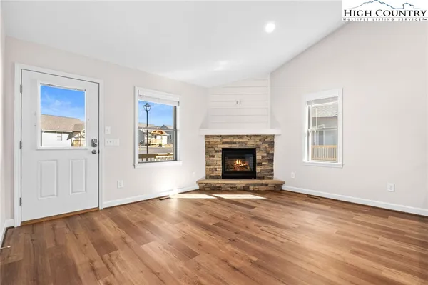 a view of an empty room with wooden floor fireplace and a window