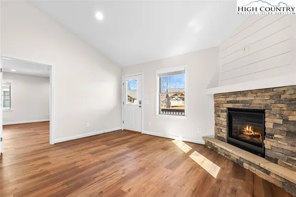 a view of empty room with wooden floor and fireplace