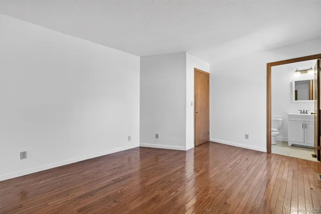 an empty room with wooden floor and a sink