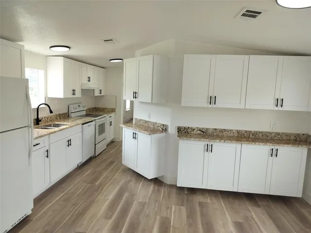 a kitchen with granite countertop white cabinets and white appliances