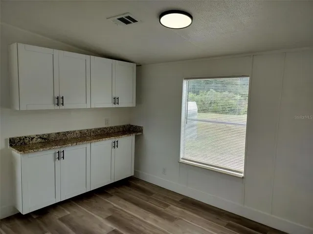 a kitchen with granite countertop cabinets stainless steel appliances a sink and a window