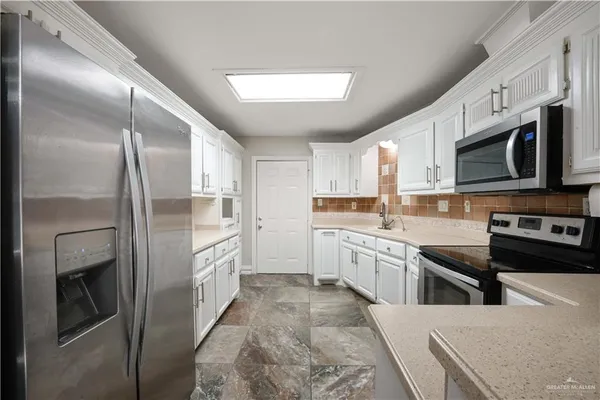 a large kitchen with stainless steel appliances kitchen island granite countertop a refrigerator and a stove top oven