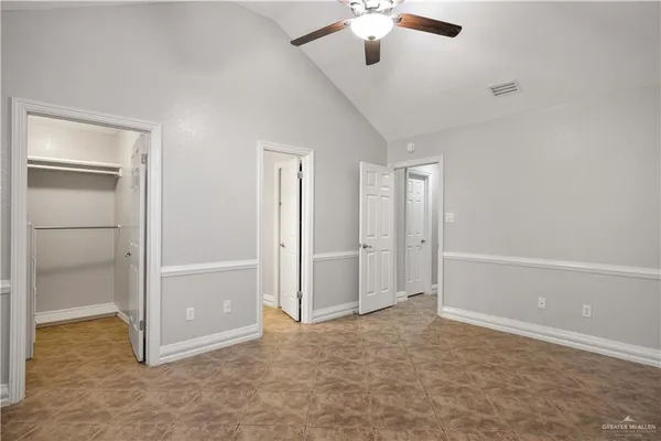 an empty room with closet and a chandelier fan