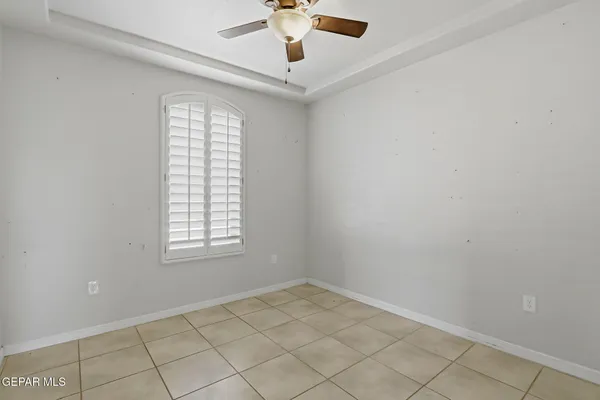 an empty room with windows and ceiling fan