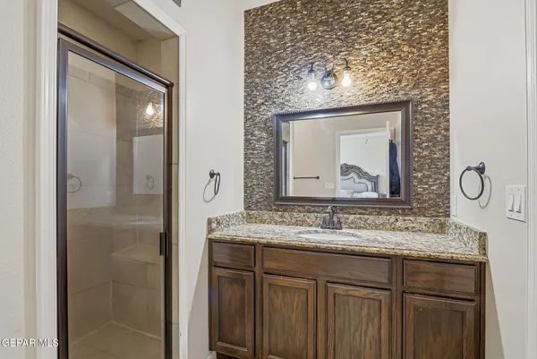 a bathroom with a granite countertop sink a mirror and a shower