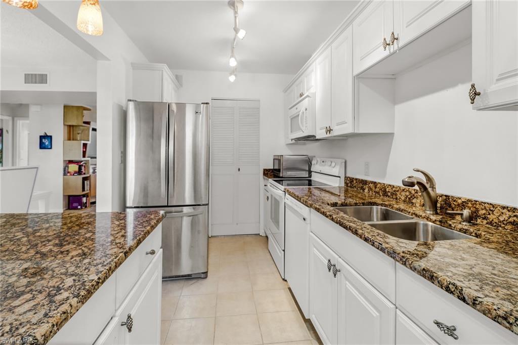 788 Park Shore Drive, Unit E32 Naples, FL 34103 - Photo 13 of 35 a kitchen with a sink a refrigerator and cabinets