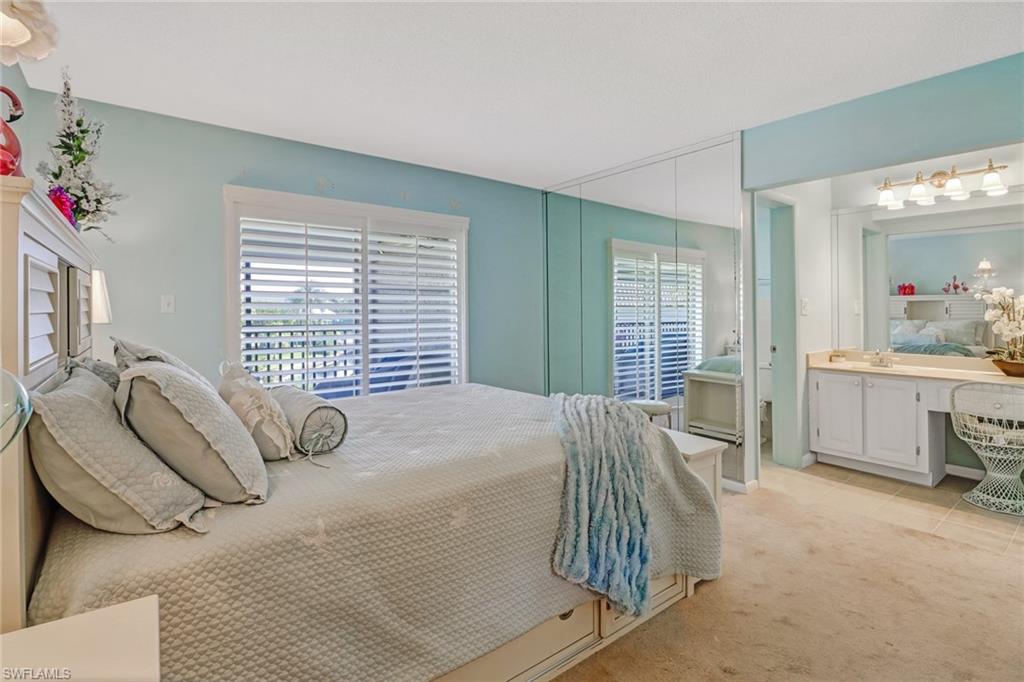 788 Park Shore Drive, Unit E32 Naples, FL 34103 - Photo 17 of 35 a bed sitting in a bedroom next to a window and dresser