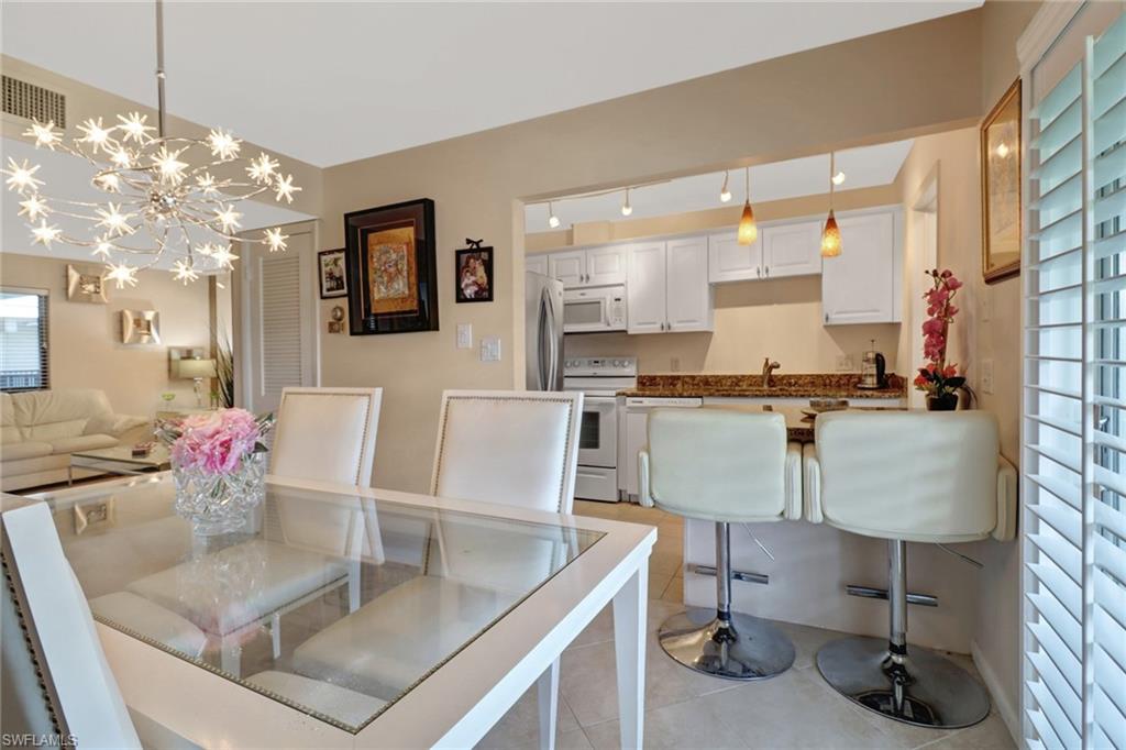 788 Park Shore Drive, Unit E32 Naples, FL 34103 - Photo 10 of 35 a kitchen with a table chairs and a living room view