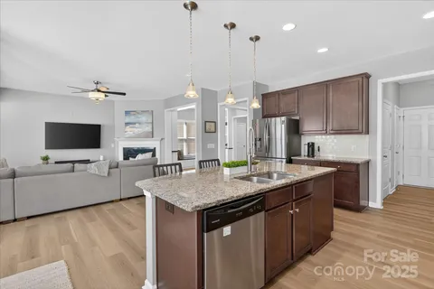 a kitchen with stainless steel appliances granite countertop a sink a stove and a wooden floor