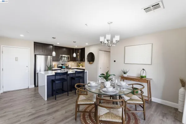 a dining room with wooden floor a chandelier a wooden table and chairs