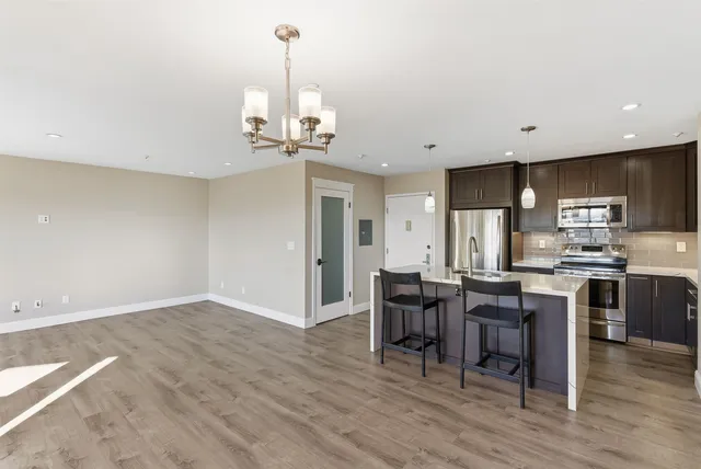 a view of a dining room and livingroom with furniture wooden floor a rug and a chandelier