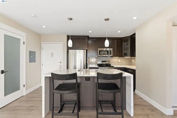 a dining area with stainless steel appliances kitchen island granite countertop a dining table chairs and a refrigerator