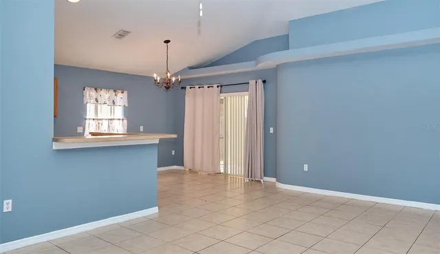 a view of an empty room with window and chandelier fan