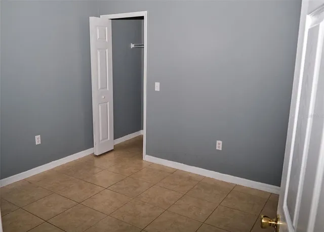 a view of an empty room with closet and a window