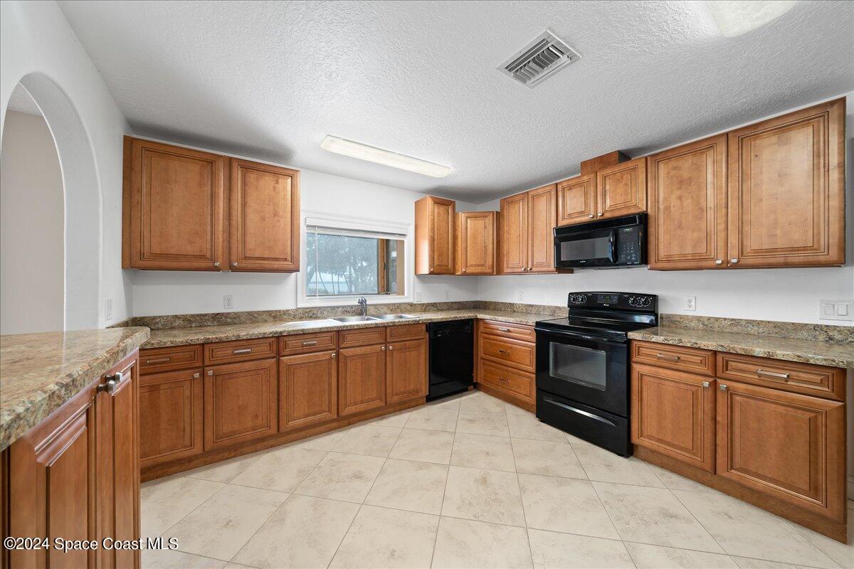 1469 Rockledge Drive Rockledge, FL 32955 - Photo 9 of 67 a kitchen with stainless steel appliances granite countertop wooden cabinets a stove top oven a sink and dishwasher