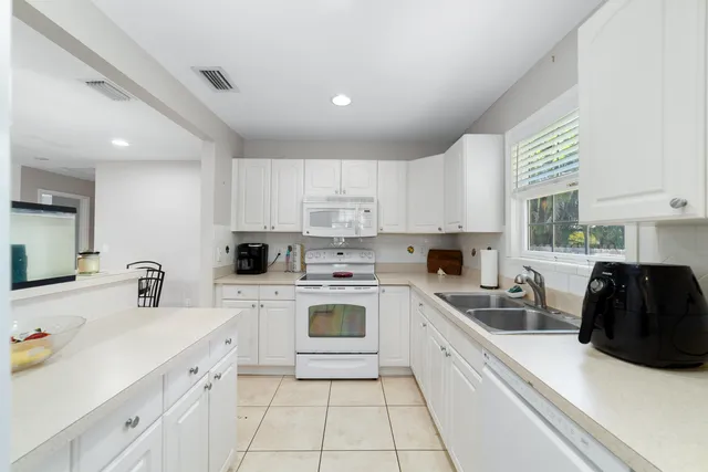 a kitchen with a sink white cabinets and white appliances