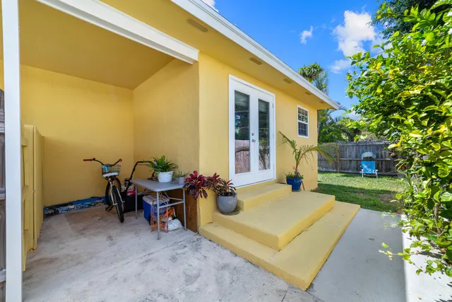 a view of a patio with a dining table and chairs with plants and wooden fence