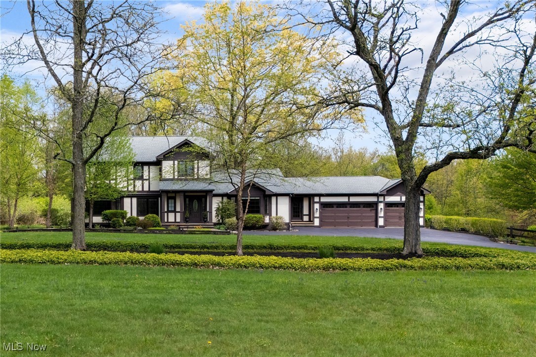 View of front facade featuring an attached garage, asphalt driveway, and a front yard