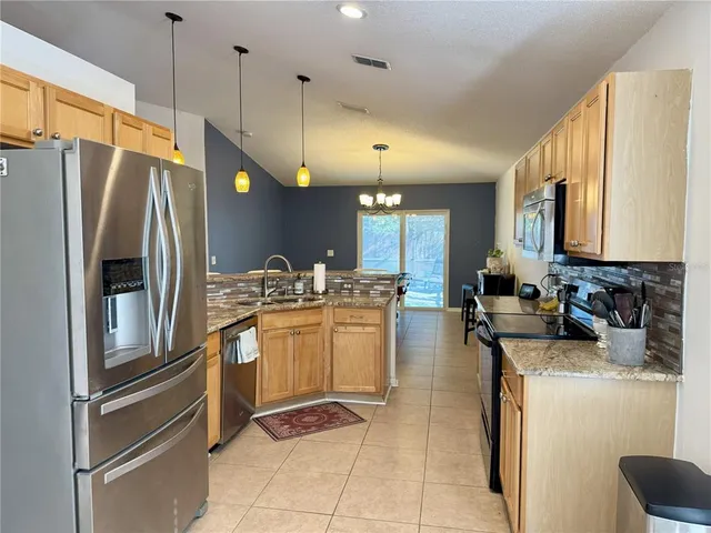 a kitchen with kitchen island granite countertop a sink a counter top space and living room view