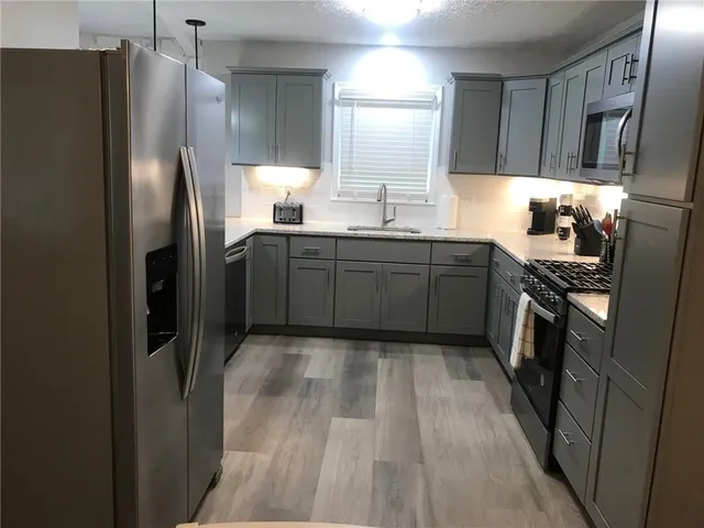 a kitchen with stainless steel appliances granite countertop a refrigerator and a sink