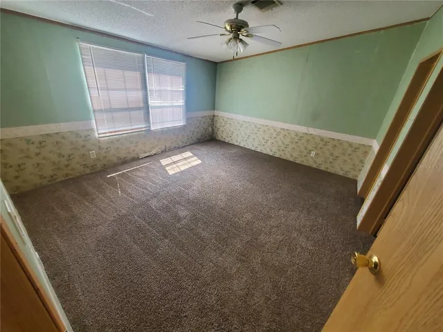 an empty room with windows and fan