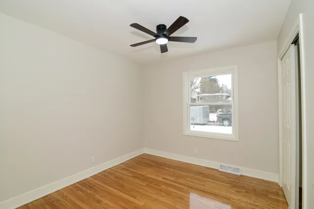 a view of empty room with wooden floor and fan