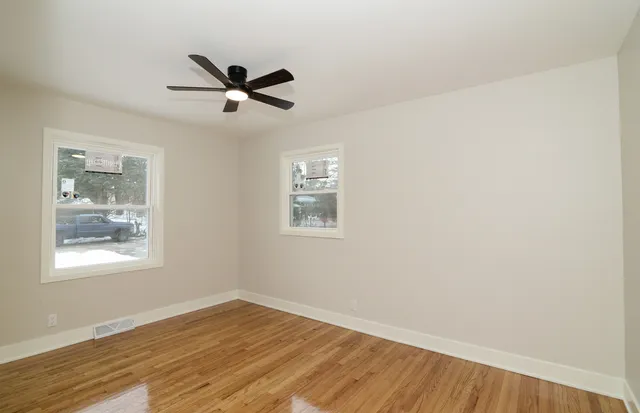 a view of empty room with wooden floor and fan