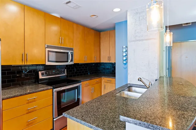 a kitchen with stainless steel appliances granite countertop a sink a stove and a microwave