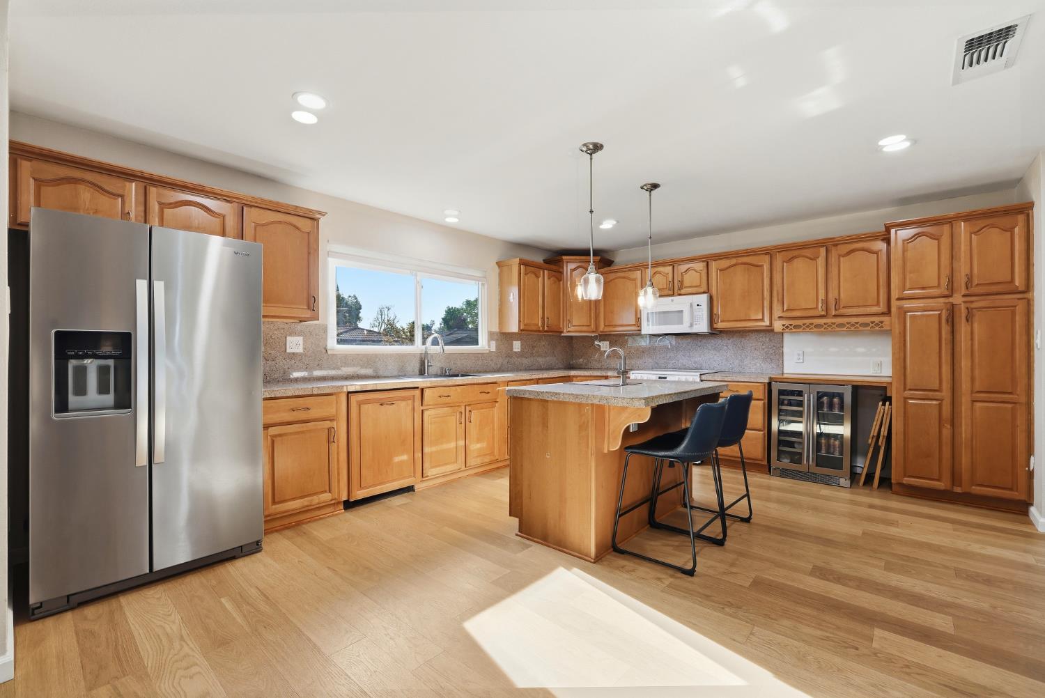 5295 Baumgart Way Carmichael, CA 95608 - Photo 6 of 46 a kitchen with stainless steel appliances kitchen island granite countertop a refrigerator a stove a sink a dining table and chairs with wooden floor