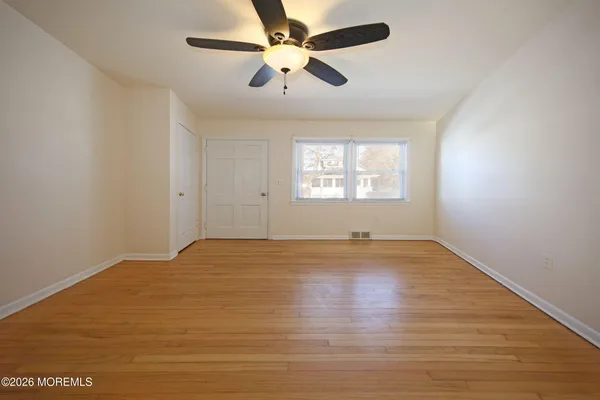 an empty room with wooden floor and windows