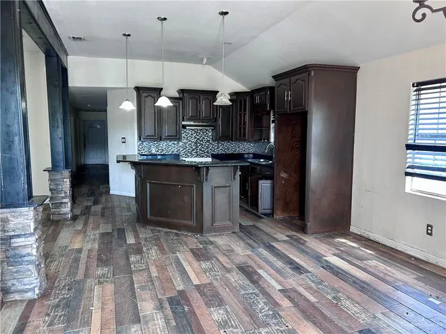 a kitchen with stainless steel appliances granite countertop a refrigerator a stove and a sink with wooden floor