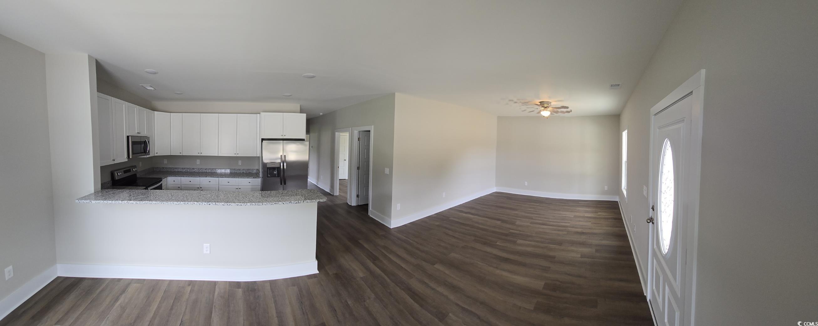 4890 Highway 319 Aynor, SC 29511 - Photo 5 of 21 Kitchen featuring white cabinetry, light stone counters, stainless steel appliances, dark wood-style flooring, and a peninsula