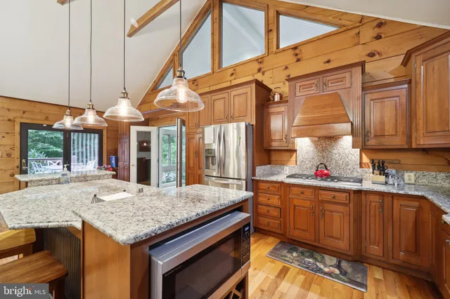 a kitchen that has a kitchen island wooden cabinets and stainless steel appliances