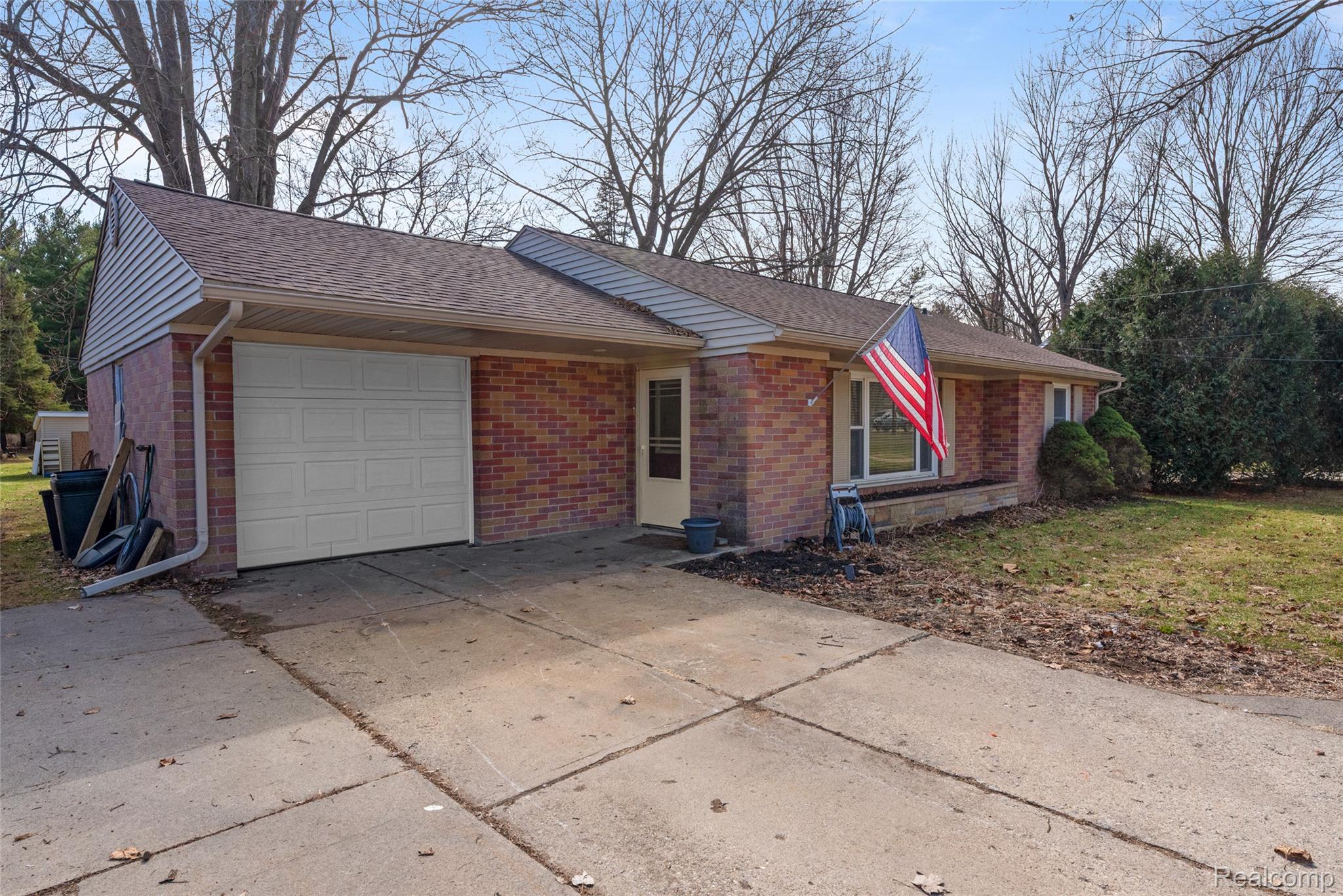 8150 Davison Road Davison, MI 48423 - Photo 2 of 25 View of property exterior featuring brick siding, driveway, a garage, a lawn, and a shingled roof