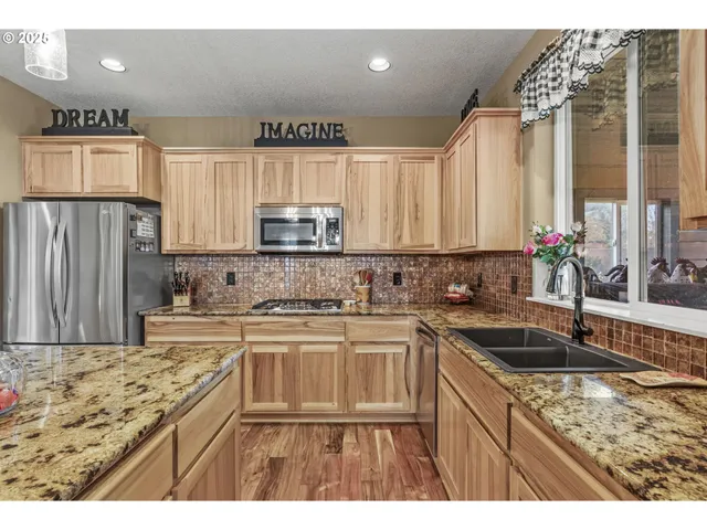 a kitchen with kitchen island granite countertop a sink stainless steel appliances and cabinets