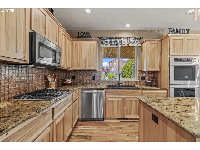 a kitchen with stainless steel appliances granite countertop a stove a sink and a microwave