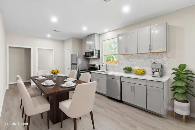 a kitchen with a dining table cabinets and wooden floor