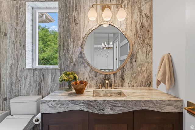 12308 Mariah Circle Draper, UT 84020 - Photo 177 of 293 Guest House Floating vanity with a sculpted stone countertop and integrated basin, set against a full-height stone accent wall
