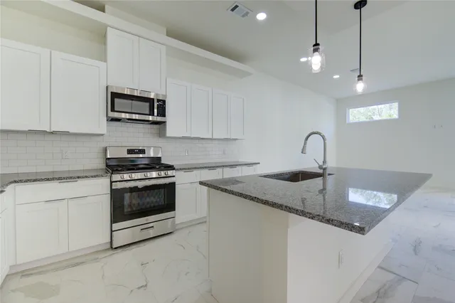 a kitchen with stainless steel appliances granite countertop a sink a stove a microwave and cabinets