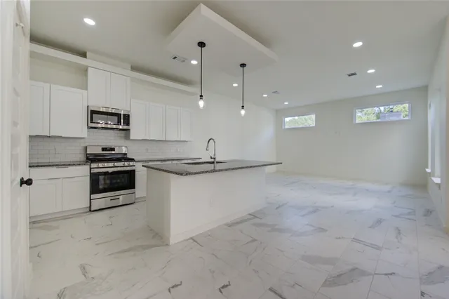a kitchen with granite countertop a stove and cabinets