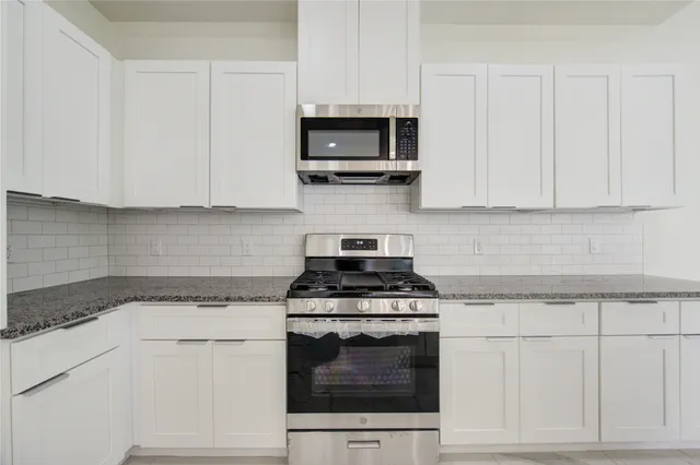 a kitchen with granite countertop white cabinets and stainless steel appliances