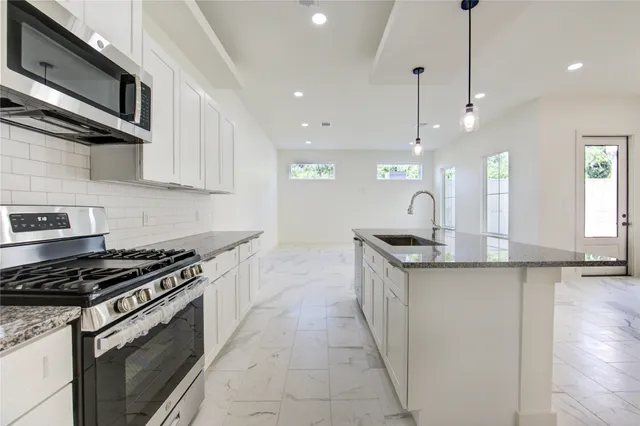 a kitchen with stainless steel appliances granite countertop a sink a stove and a wooden floors
