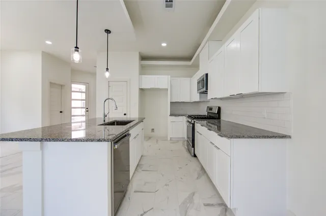a large kitchen with granite countertop a sink a counter top space and cabinets