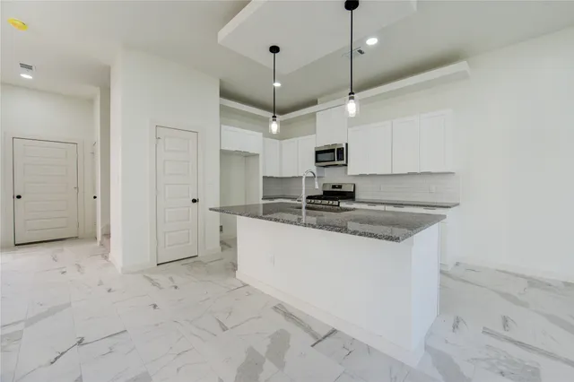 a kitchen with kitchen island a sink a counter space appliances and cabinets