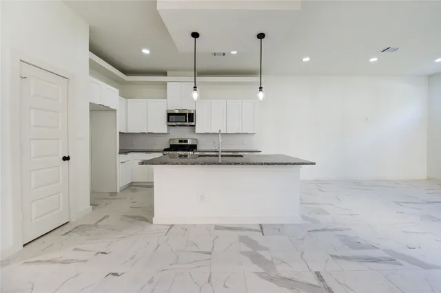 a view of kitchen with stainless steel appliances granite countertop a stove a sink and a refrigerator