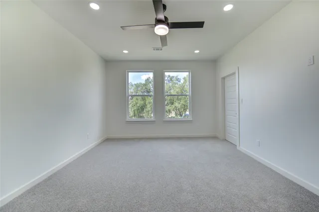 en empty room with windows and ceiling fan