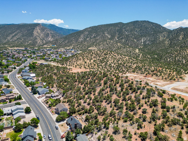 790 East Fiddlers Canyon Road Cedar City, UT 84721 - Photo 26 of 35 Expansive land parcel featuring natural desert vegetation, a winding paved road, and distant mountain backdrops