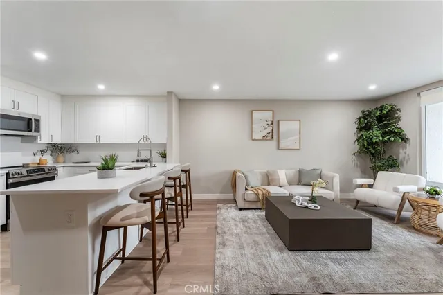 a living room with furniture a rug kitchen view and a window