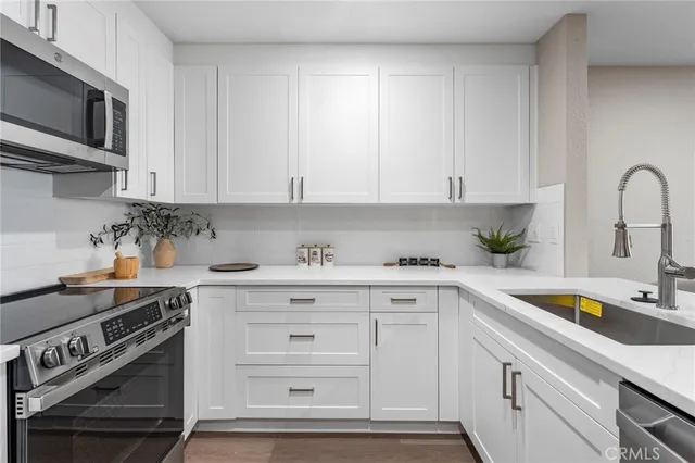 a kitchen with stainless steel appliances granite countertop a sink a stove and cabinets